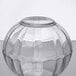 An Arcoroc clear glass bowl with a curved edge on a reflective surface.