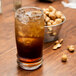 A Libbey Cascade cooler glass of iced tea with a bowl of peanuts.