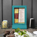 A Menu Solutions sky blue wood menu frame on a table with food.