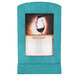 A Sky Blue wood menu tent frame with angled base on a table displaying a menu with a picture of a glass of wine.