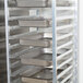 A Regency aluminum steam table pan rack with metal trays on it.