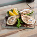 A Libbey square glass salad plate with oysters and a lemon.