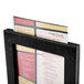 A Menu Solutions black framed wood menu tent on a table with a menu inside.