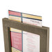 A Menu Solutions weathered walnut wood frame with an angled base holding a menu card.
