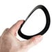 A hand holding a black rubber gasket with a circular ring shape.
