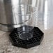 A clear plastic cup on a black Choice octagonal drip tray with removable grate.