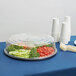 A WNA Comet black plastic catering tray with vegetables and utensils on it.