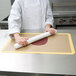 A person rolling a roll of dough with an Ateco plastic rolling pin.