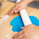 A hand rolling out dough with a white Ateco plastic rolling pin.