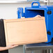 A woman holding a rectangular Cambro ThermoBarrier in a school kitchen.