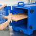 A person opening a blue Cambro box with a blue handle.