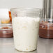 A clear plastic Fabri-Kal deli container filled with white and brown pudding.