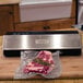 A piece of meat in a vacuum bag on a counter next to a Weston Professional Advantage Vacuum Packaging Machine.
