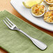 A plate of stuffed clams with a lemon wedge and an Acopa Saxton oyster fork on a green cloth.
