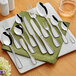 A set of Acopa stainless steel dinner forks on a table with a napkin