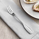 An Acopa Scottdale stainless steel oyster fork on a napkin next to a plate of oysters.