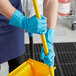 A person in blue Cordova latex rubber gloves using a yellow mop handle.