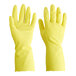 A close-up of a pair of yellow Cordova latex rubber gloves with a finger up.