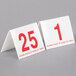 Two white Cal-Mil table tents with red numbers 1 to 25 on a table.