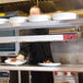 An Avantco strip warmer above a counter with a plate of food on it.