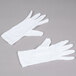 A pair of Cordova white stretch nylon inspector's gloves on a gray surface.