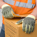 A person wearing Cordova heavy duty work gloves holding a box.