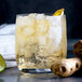A glass of Narvon ginger ale with ice, ginger root, lime, and lemon slices.