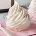 A close up of a clear plastic dessert cup filled with swirled white soft serve.