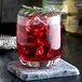 A glass of Narvon cranberry juice syrup with ice and a sprig of rosemary.