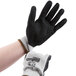 A hand wearing a Cordova Commander cut resistant glove with black foam nitrile coating.