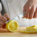 A person using a Choice serrated paring knife to slice a lemon.