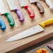 A white Choice chef knife on a cutting board with other knives.