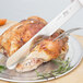 A Choice white straight edge slicing knife cutting a turkey on a plate.