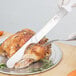 A Choice serrated bread knife with a white handle cutting a turkey.
