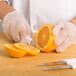 A person wearing gloves uses a Choice smooth edge paring knife to slice an orange.