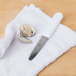 A Choice stainless steel clam knife and clamshell on a towel.