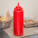 A red Choice wide mouth squeeze bottle on a table with fries.