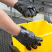 A person wearing a Cordova black sandpaper glove holding a yellow bucket.