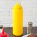 A table with a plate of food and a yellow Choice wide mouth squeeze bottle on it.