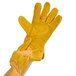 A hand wearing a yellow Cordova warehouse glove with russet leather palm coating.