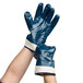 A pair of hands wearing blue Cordova warehouse gloves with white lining.