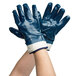 A pair of hands wearing blue Cordova nitrile gloves with white and blue stripes on the cuffs.