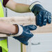 A person wearing Cordova blue nitrile gloves holding a piece of wood.