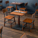 A Lancaster Table & Seating wooden table and two chairs in a restaurant.