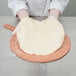 A person in white gloves using an American Metalcraft pizza peel to make a pizza.