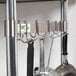 A Regency stainless steel pot rack with utensils hanging from it.