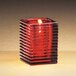 A Sterno red ribbed glass candle holder with a lit candle.