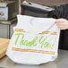 A woman holding a white LK Packaging plastic take out bag with green "Thank You" text.