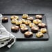 A Matfer Bourgeat Exal aluminum sheet pan with brown and white square cookies on it.