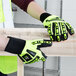 A person wearing Cordova Hi-Vis lime green and yellow heavy duty work gloves holding a piece of wood.
